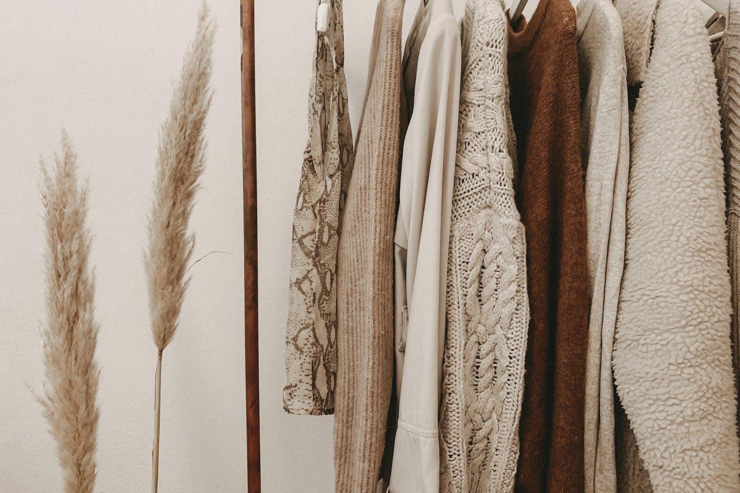 Strickwaren und Jacken in neutralen Farben an einer Kleiderstange