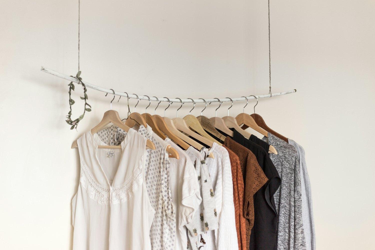 Une petite collection de hauts et de blouses sur des cintres en bois